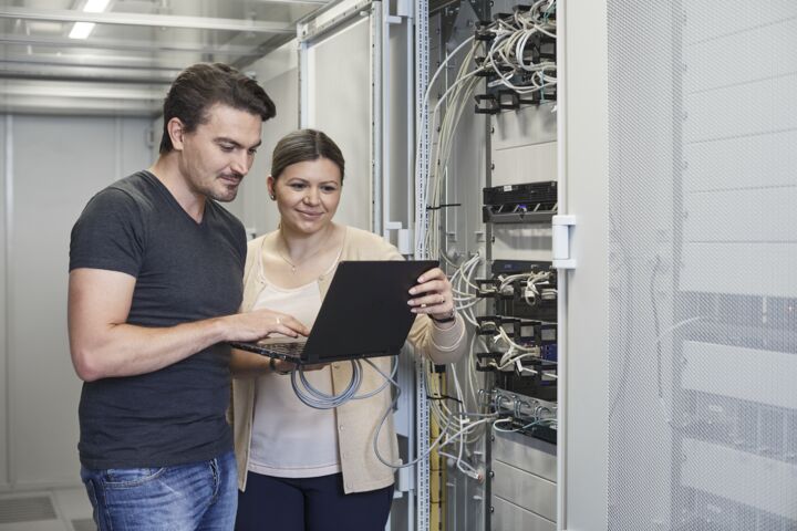 GEZE Mitarbeiter vor einem Schaltschrank schauen auf einen Laptop