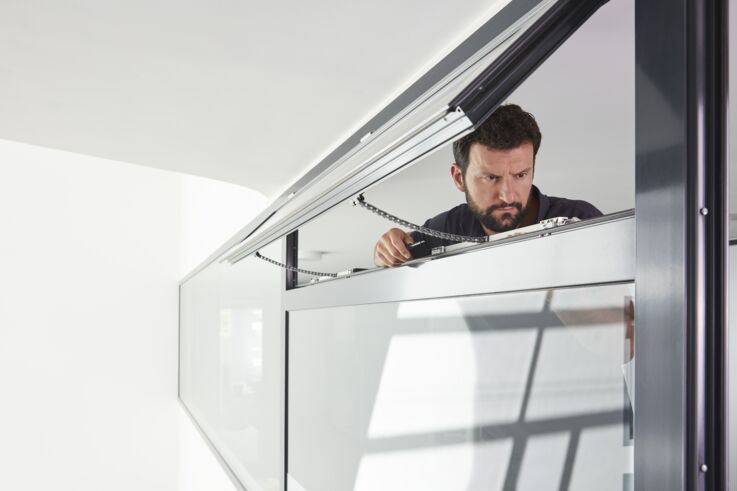 A GEZE service technician inspects a tilted fanlight window
