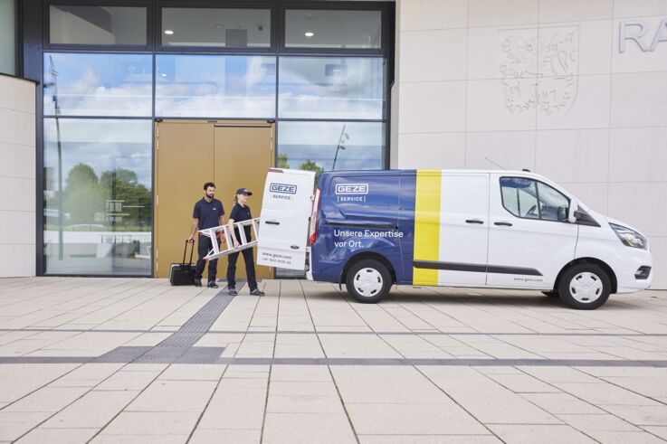 Two GEZE service technicians loading the service van outside a building