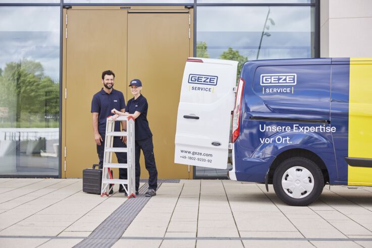 Two GEZE service engineers stand in front of the GEZE service van with a ladder