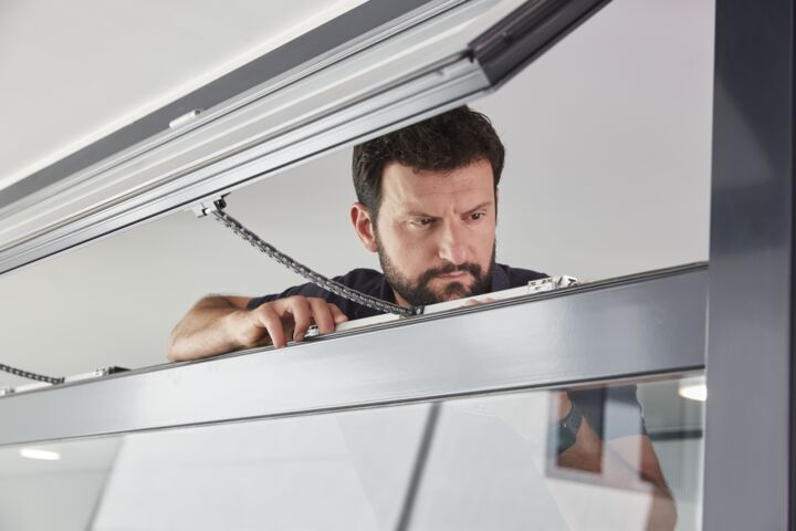 A GEZE service technician carrying out maintenance on a window