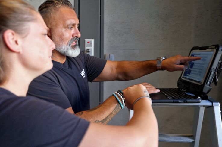 Deux techniciens de maintenance GEZE consultent un ordinateur portable et discutent