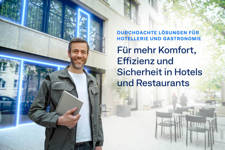 Mann mit Laptop steht vor einem Hotelgebäude