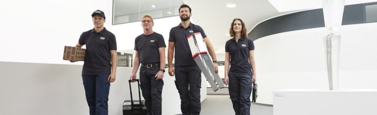Four GEZE service technicians walk with their work materials