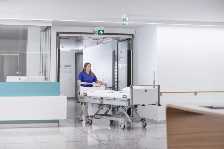 Eine Krankenschwester schiebt ein Bett durch eine Tür im Krankenhaus