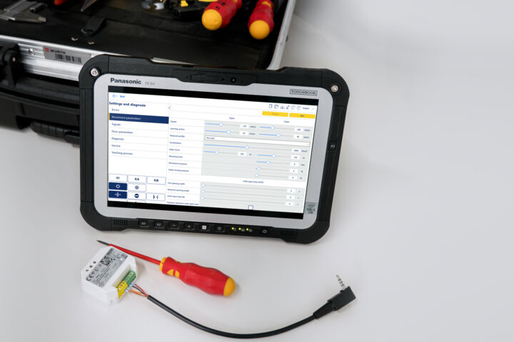 Toughpad de service avec interface logicielle ouverte, à côté un module Bluetooth, un tournevis et une boîte à outils à l'arrière-plan.