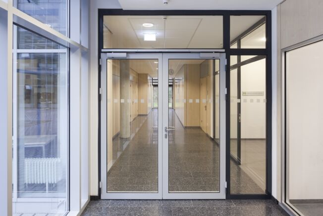 Gleitschienentürschließer TS 5000 R-ISM Brandabschnittstür mit TS 5000 R-ISM, Gleitschienentürschließersystem für zweiflügelige Türen mit Schließfolgeregelung und Rauchschalter, verbaut in der Berufsschule in Friedrichshafen.