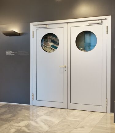 Gleitschienentürschließer TS 5000 R-ISM, Showroom Leonberg TS 5000 R-ISM, Gleitschienentürschließersystem für zweiflügelige Türen mit Schließfolgeregelung und Rauchschalter, verbaut im Showroom der GEZE GmbH in Leonberg.