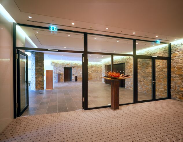 Corridor area with glass partitioning wall and open glass door.
