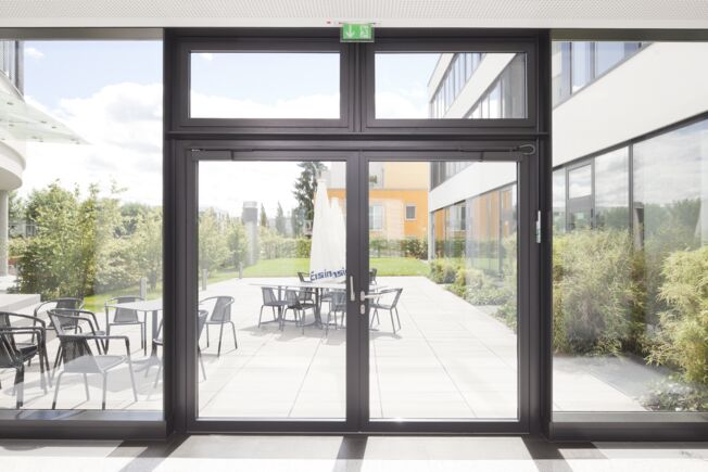Fels  szerelés , csúszósínes ajtózár TS 5000 L-ISM, beépítve a Häussler Global Office GmbH-nál, Stuttgartban. Fels  szerelés , csúszósínes ajtózár rendszer, pánttal ellentétes oldalon, kétszárnyú ajtókhoz antipánik funkcióval és csukássorrend szabályozással.