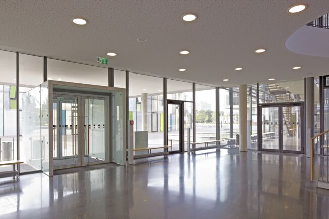 Eingang Berufsschulzentrum mit Drehtüren und Notausgang Das Zusammenspiel des TS 5000, Slimdrive SD Servo und TS 5000 R-IS führt dazu, dass der optimale Begehkomfort erzeugt wird sowie wie maximale Barrierefreiheit.