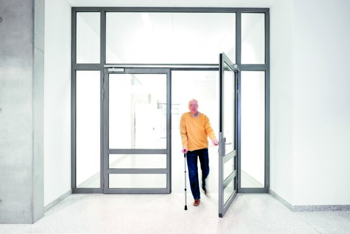 Elderly man walking through a glazed double-leaf door
