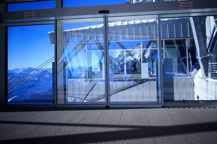 Porta scorrevole automatica con vista panoramica sul paesaggio innevato da una stazione a monte.