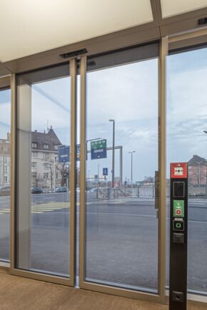 Automatischer Schiebetürantrieb Powerdrive PL-FR mit Stele für die Schalter im Eingangsbereich des Grosspetertower in Zürich Automatisches Linear-Schiebetürsystem in Flucht- und Rettungswegen für große und schwere Türen