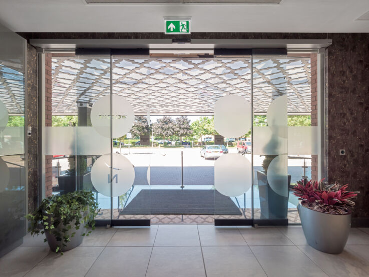 View from a hotel entrance to the outside through an open glass sliding door.