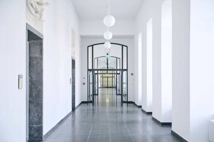 Bright corridor in Mannheim Palace with high ceilings and a large, open glass door with black metal frame.
