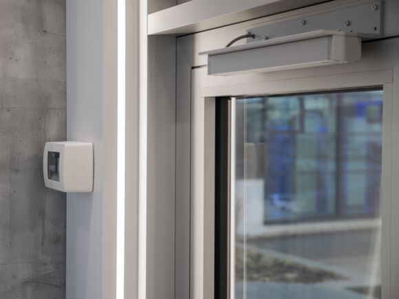 SHEV air inlet door with a K 600 T retractable arm drive and the GC Lock Control SHEV additional control unit for motor locks. GEZE offers a comprehensive smoke and heat extraction solution that includes the smoke and heat extraction control panel, door drives, self-locking panic locks and the GC Lock Control SHEV additional control unit for motor locks. The GC Lock Control SHEV guarantees the safe operation of motor locks on SHEV air inlet doors in the event of an alarm, and at the same time functions as a central connection point for all system parts to the smoke and heat extraction system.