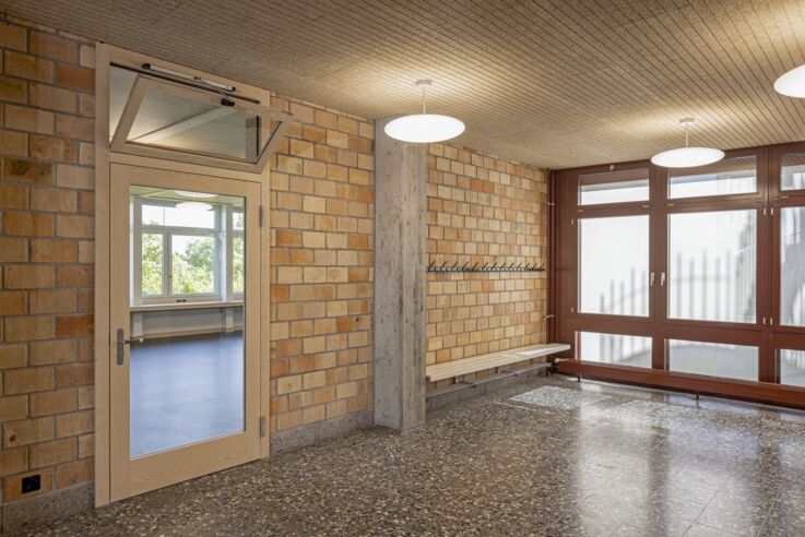 Ansicht des Schulflurs mit einer Glastür, an der das obere Fenster gekippt ist.