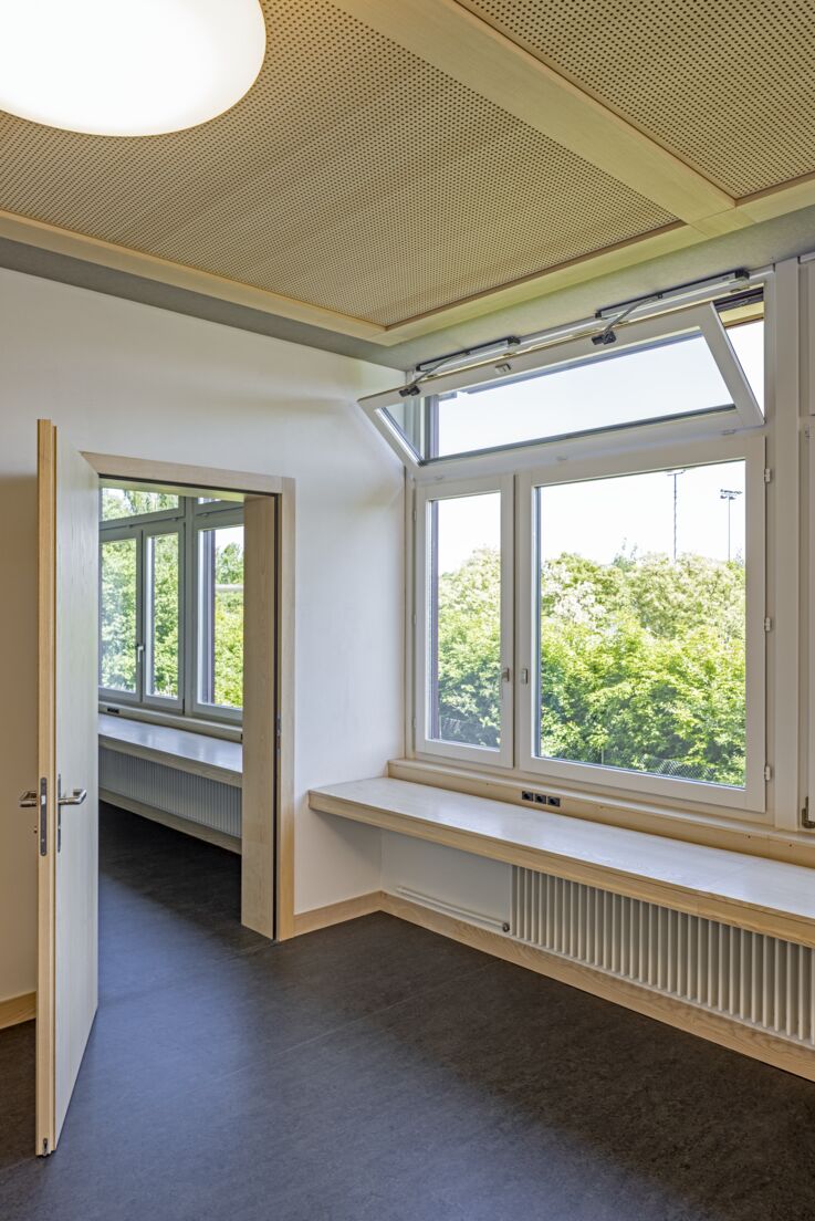 Klassenräume mit geöffneter Durchgangstüre und Fensterfronten rechts