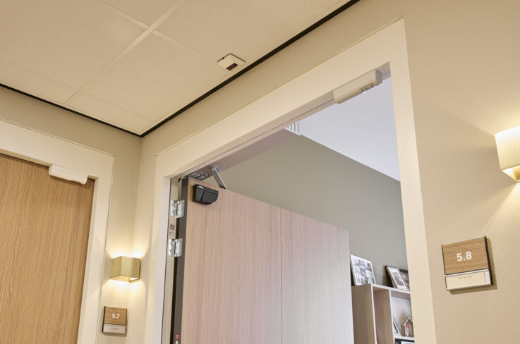 View into a door frame at an open door with a sensor for automatic doors.