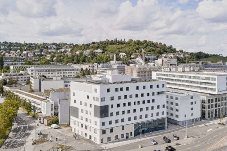 Luftfoto av sykehuset i Stuttgart i urbane omgivelser, omgitt av trær og andre bygninger i bakgrunnen.