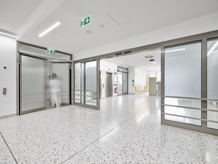 Lys gang i et moderne bygning med skyvedører og heis 