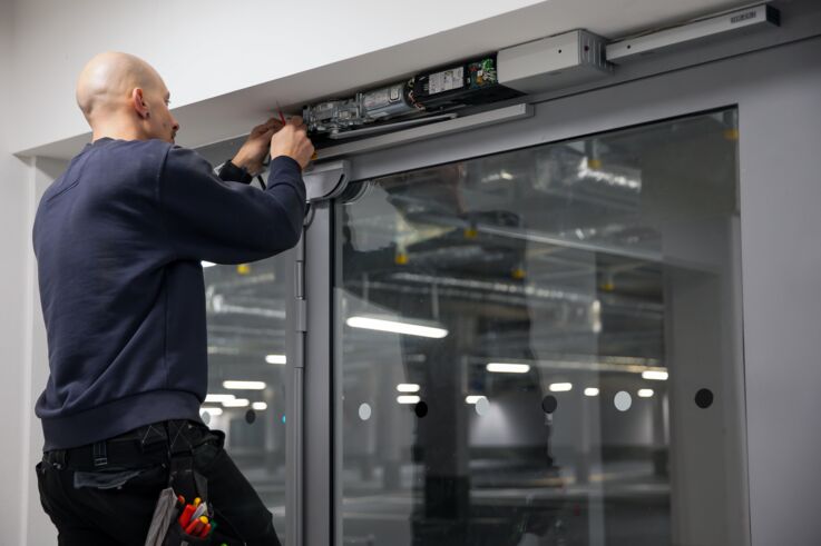 GEZE Service technicians installing a door closer on a large glass door
