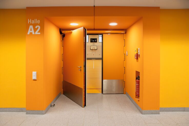 Oransje dør til hall A2 i idrettsanlegget på utdanningscampus Freiham